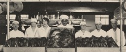 Gulley with cooking staff standing behind roasted turkeys.
