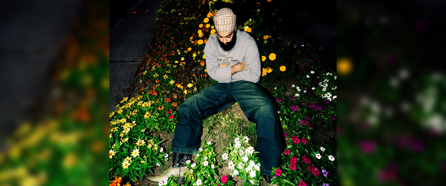 Kabir Chawla models clothing in a bed of flowers.