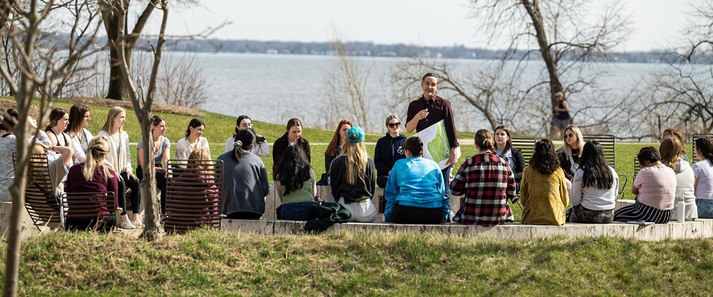 Students sit around a fire circle and listen to tour guide Omar Poler ’07, MA’10. 