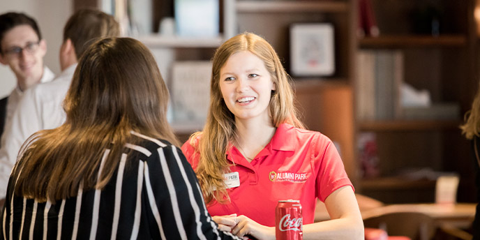 An Alumni Park worker talking with an attendee