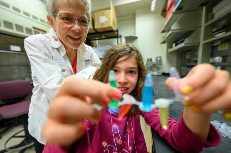 Jeanne Nye and her granddaughter Charlotte Nye admire a growing chain of test tubes whose colors of green, red, blue, and yellow represent the four nucleotide bases of DNA. PHOTO BY: ALTHEA DOTZOUR