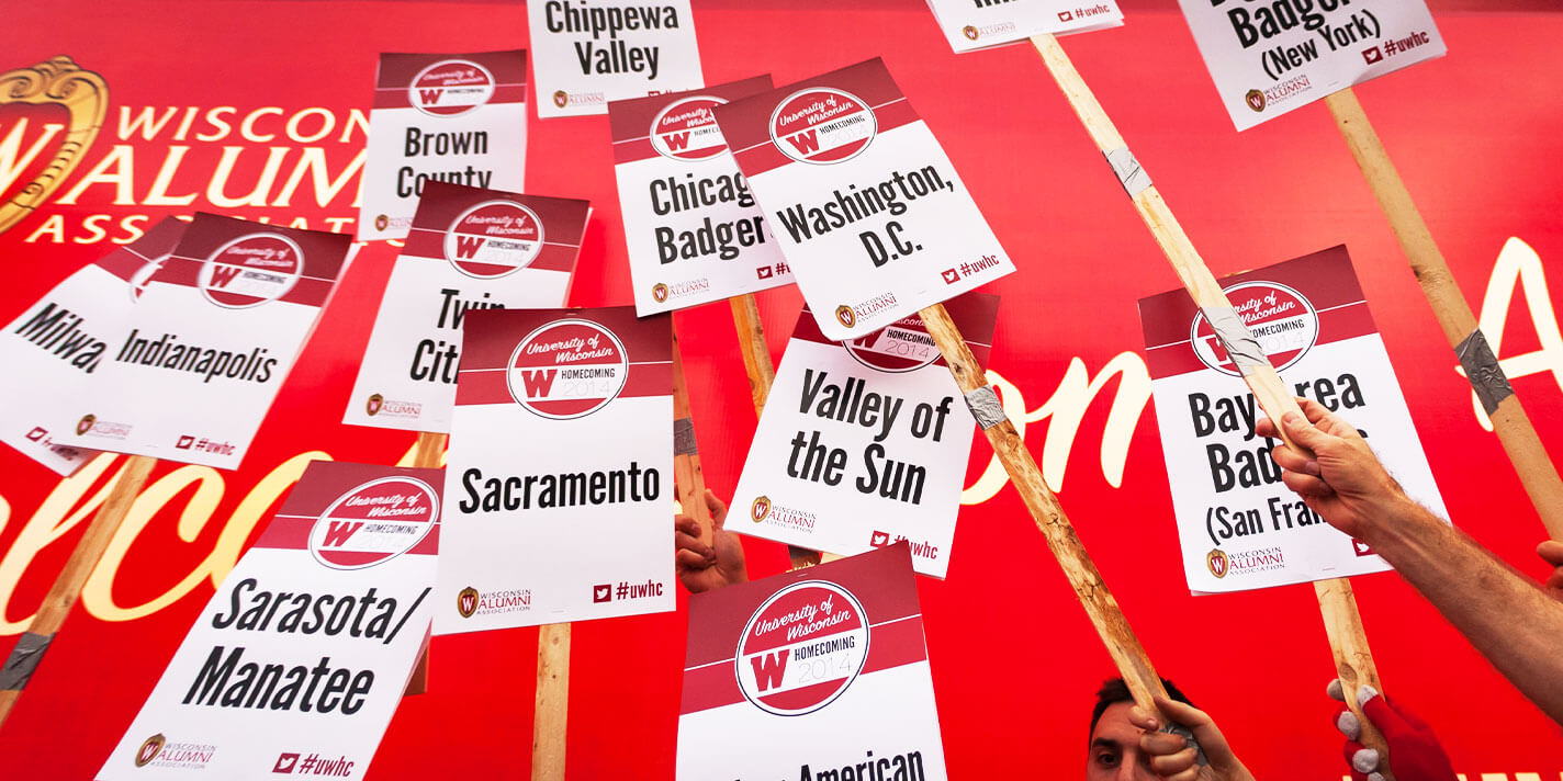 Groups of people holding up signs indicating where they're from