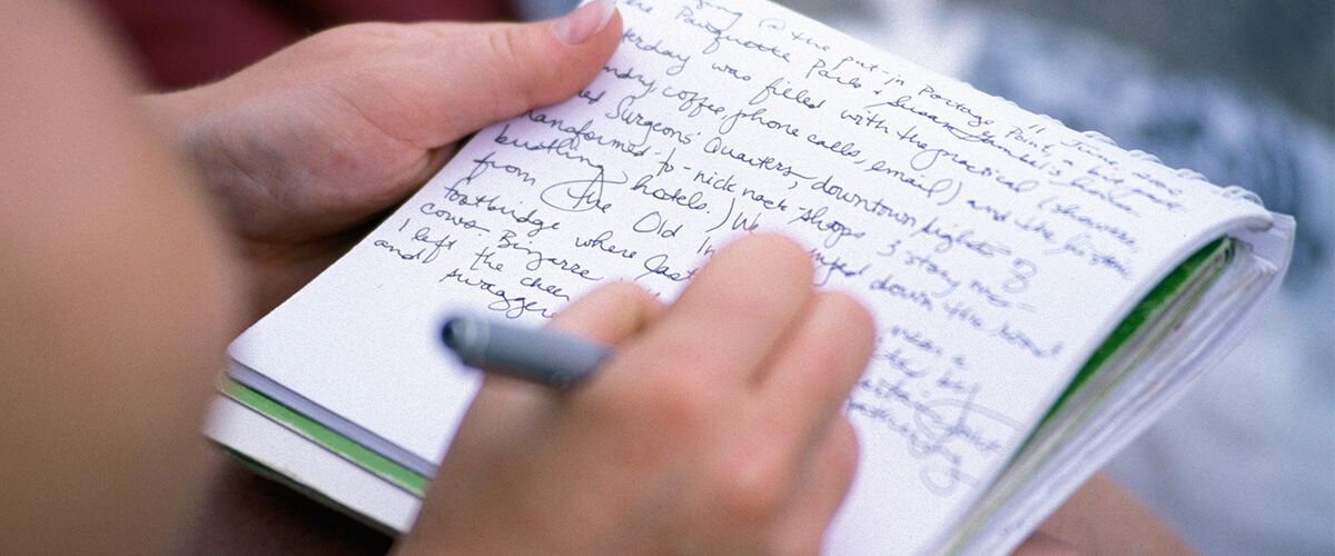A photo of a hand writing in a notebook