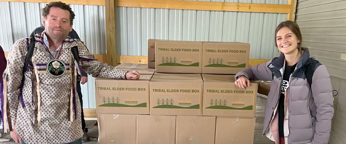 Cornelius pictured in front of boxes of food meant for tribal elders.