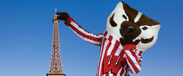 Bucky Badger standing next to the Eiffel Tower.