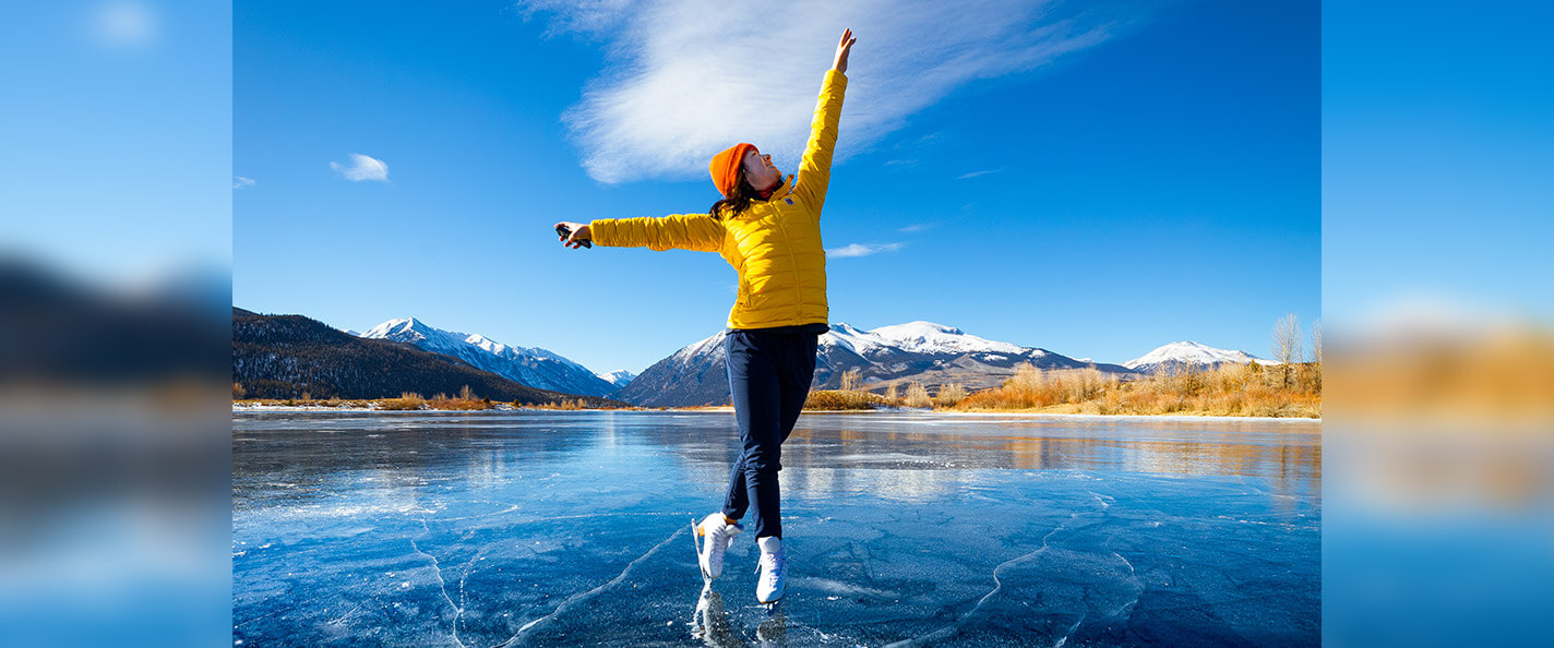 Huang skates on lake with mountains in the background.