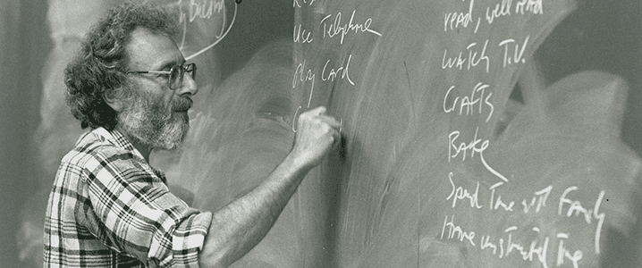 Professor writing on chalkboard.